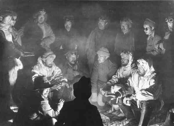 Membrii expediției adunați în jurul unui foc de tabără, în timpul popasurilor nocturne prin regiunile muntoase din Himalaya.