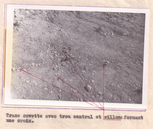 O fotografie alb-negru de arhivă, cu un text descriptiv în franceză, care arată urma circulară centrală și adânciturile lăsate pe solul câmpului de către picioarele de aterizare ale navei.