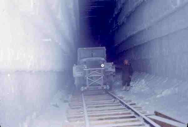 Un vehicul utilitar pe șine sau șenile în interiorul unui tunel adânc săpat în calota glaciară.