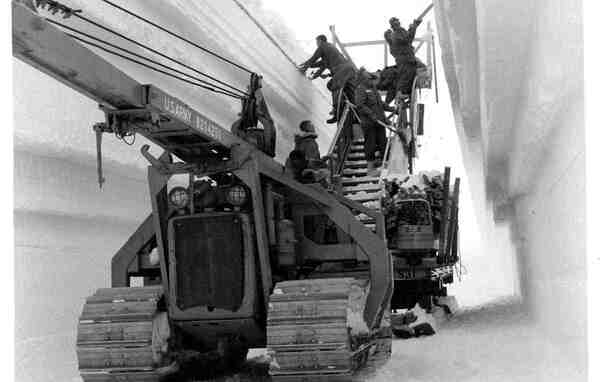 O structură interioară a tunelurilor săpate în gheață la Camp Century, prezentând utilaje și pereți masivi de gheață.